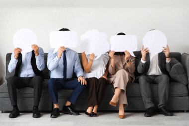 Boş konuşma baloncukları olan bir grup iş adamı koltukta oturuyor.