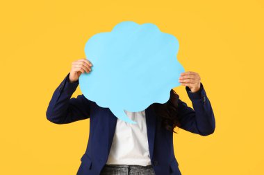 Sarı arka planda boş konuşma balonu olan genç bir iş kadını.