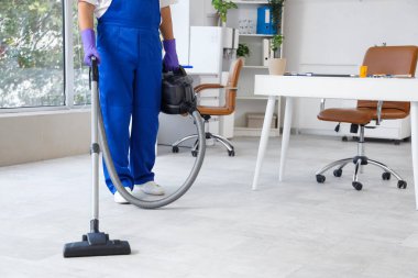 Temizlikçi ofiste yerleri süpürüyor.