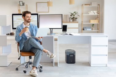 İş yerinde laptoplu ve kahveli erkek programcı.