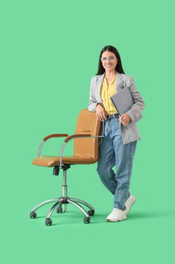 Dosyası ve yeşil arka planda ofis sandalyesi olan genç bir iş kadını.