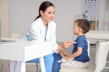 Klinikte ateşini ölçen küçük tatlı bir oğlu olan kadın bir çocuk doktoru.