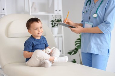 Kanepede tatlı küçük bir çocuk klinikteki çocuk doktorunu ziyaret ediyor.