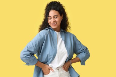 Sarı arka planda şık mavi gömlekli güzel bir Afro-Amerikalı kadın.