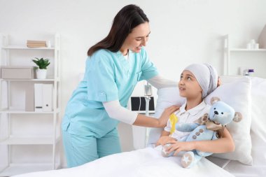 Kemoterapiden sonra sarı kurdeleli ve klinikte hemşirelik yapan küçük bir kız. Çocukluk kanseri farkındalığı