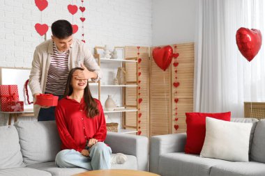 Sevgililer Günü 'nde sevgilisinin gözlerini kapayan hediyeli genç bir adam.