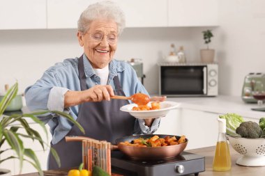 Son sınıf öğrencisi kadın mutfakta kızarmış makarna hazırlıyor.
