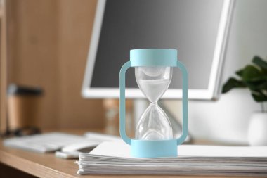 Ofisteki kağıtların üzerindeki kum saati, yakın çekim.