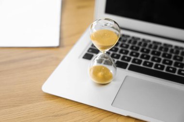 Ofiste dizüstü bilgisayarlı kum saati, yakın plan.