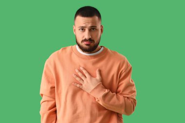 Apologetic young man on green background clipart