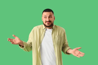 Apologetic young man on green background clipart