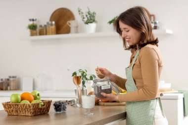 Mutfaktaki masada chia tohumu yoğurdu yapan genç bir kadın.