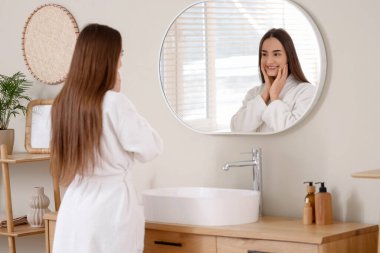 Evde duştan sonra aynaya bakan genç bir kadın.