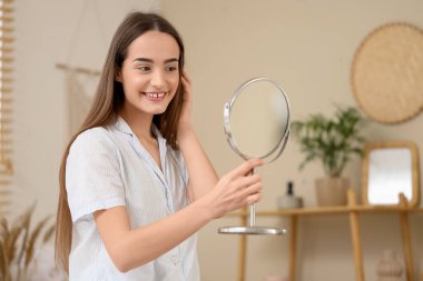 Evde aynaya bakan genç bir kadının sabahı.