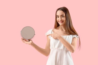 Pembe arka plandaki aynaya bakan genç kadın.