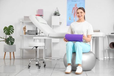 Rehabilitasyon merkezinde köpük silindirli kadın fizyoterapist.