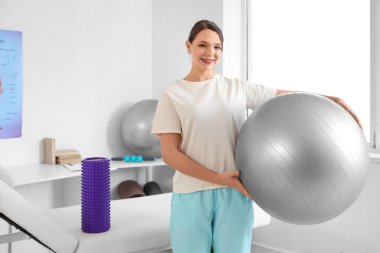 Fitball ve köpüklü kadın fizyoterapist rehabilitasyon merkezinde kanepede yatıyor.