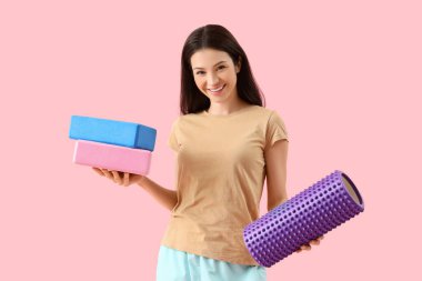 Köpük silindirli ve pembe arka planda blokları olan genç bir kadın.