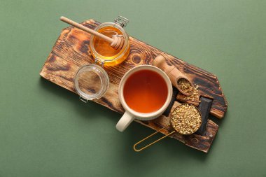 Yeşil zemin üzerinde bal olan bir fincan sıcak karabuğday çayı ve kavanoz