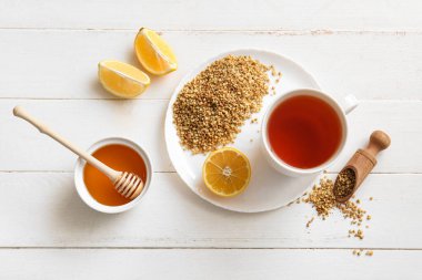 Limonlu sıcak karabuğday çayı ve beyaz ahşap arka planda bir kase bal.