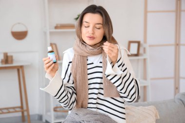 Hasta genç kadın evde öksürük şurubu içiyor.