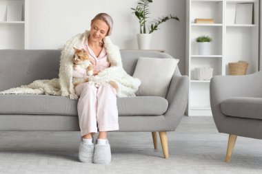 Pijamalı, terlikli ve evdeki kanepede oturan güzel bir kadın.