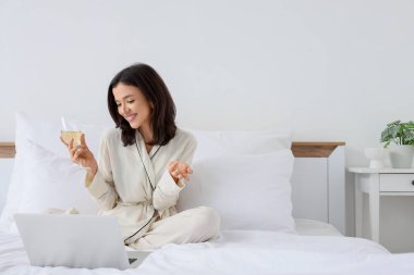 Şarabı olan genç bir kadın yatak odasında online randevuya çıkıyor.