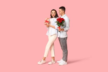 Sevgi dolu genç bir çift hediye kutusu ve pembe arka planda güzel güller. Sevgililer Günü 'nün kutlaması