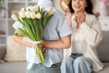 Annesini evde selamlayan laleli şirin bir çocuk. Uluslararası Kadınlar Günü
