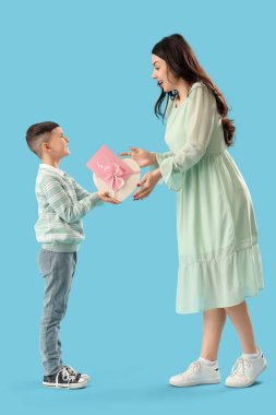 Sevimli küçük çocuk mavi arka planda Uluslararası Kadınlar Günü 'yle annesini selamlıyor.