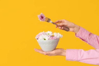 Sarı arka planda güzel çiçekli, çatal ve kâse tutan kadın.