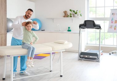 Rehabilitasyon merkezinde kanepede uzanan fizyoterapisti olan tatlı küçük bir kız.