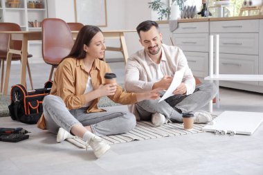 Mutfakta kahve içip, mobilyaları elle monte eden mutlu bir çift.