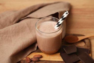 Bir bardak çikolatalı süt ve tahta zemin tozlu kaşık.