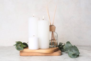 Sazlık yayıcı ve beyaz arkaplanda okaliptüs dalları ile mum yakmak