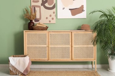 Çimen, kitap, şapka ve resim dolu çekmeceler yeşil duvarda.