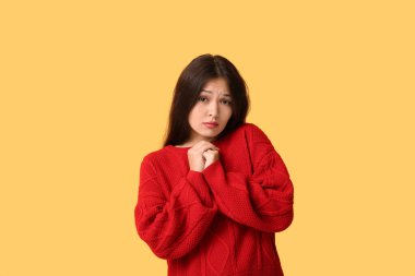 Beautiful young Asian apologizing woman on yellow background clipart