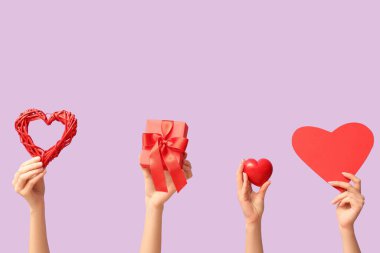 Farklı kalpleri olan kadın elleri ve leylak arkaplanlı hediye kutusu. Sevgililer Günü kutlaması