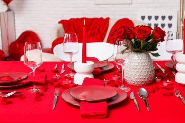Sevgililer Günü için hazırlanmış şölen masası kırmızı güller ve evde yanan mumlarla süslenmiş.