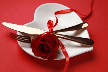 Kırmızı arka planda gül olan Sevgililer Günü için masa ayarları, yakın plan