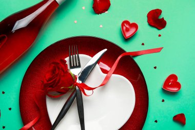 Sevgililer Günü için yeşil arka planda gül ve mumlarla birlikte masa ayarı