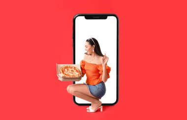 Lezzetli pizzası ve kırmızı arka planda büyük akıllı telefonu olan güzel genç bir kadın.
