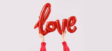 Açık arkaplanda balonlardan yapılmış aşk sözcükleri olan eller. Sevgililer Günü kutlaması