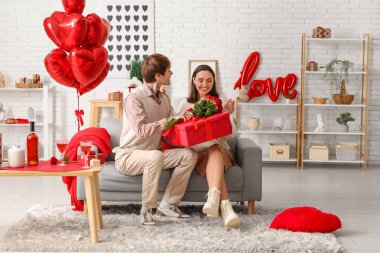 Genç adam sevgilisini sevgililer gününde evde karşılıyor.