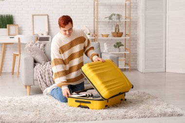 Genç adam eve gitmek için bavulunu topluyor.