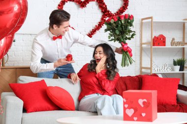 Genç adam sevgililer gününde sevgilisini gül ve hediyeyle karşılıyor.