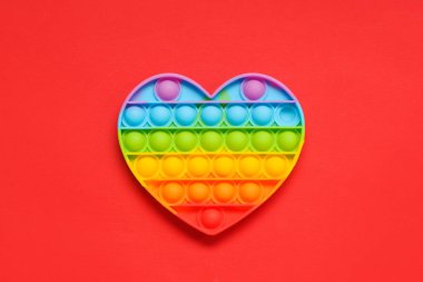 Kırmızı arka planda kalp şeklinde bir oyuncak var. Sevgililer Günü kutlaması