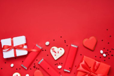 Kalp şeklinde kurabiyeleri ve kırmızı arka planda hediye kutuları olan lezzetli çikolatalar. Sevgililer Günü kutlaması