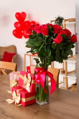 Gift boxes and bouquet of roses on wooden table in kitchen, closeup. Valentine's Day celebration clipart