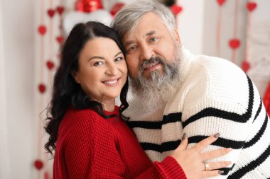 Güzel, mutlu, olgun bir çift dekoratif odada sarılıyor. Sevgililer Günü kutlaması